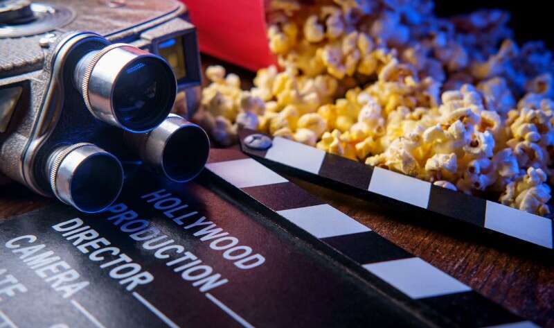 Jak popularne są polskie filmy? Na zdjęciu kamera, popcorn i rekwizyty filmowe.