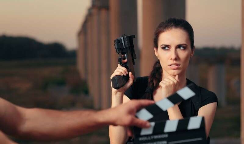 CO cechuje dobre filmy akcji? Na zdjęciu aktorka z pistoletem przed sceną.